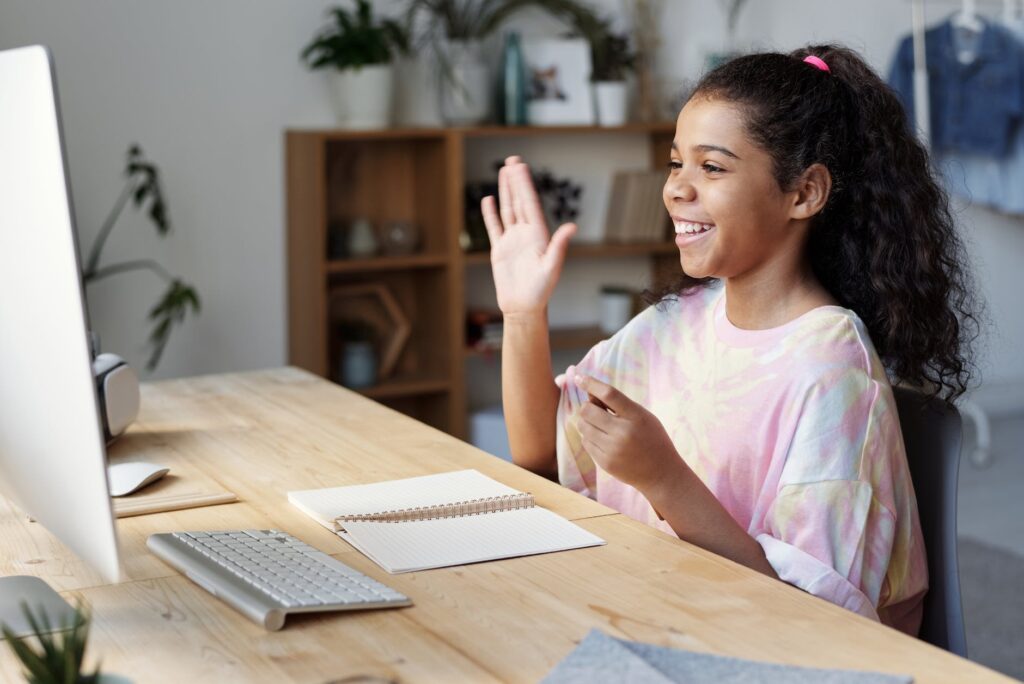 woman in pink shirt sitting by the table while smiling